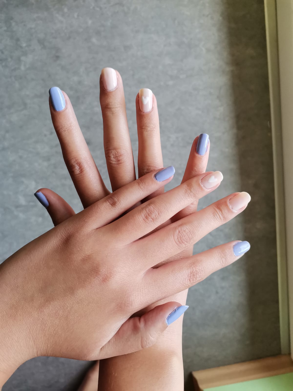 Pastellfarbende Nägel mit einem Herz am Ringfinger